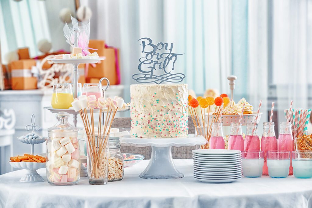 "Boy or girl" cake and different treats for baby shower party on table indoors
