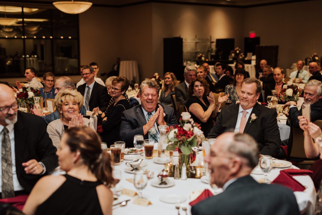 Large indoor gathering of people sitting at tables celebrating