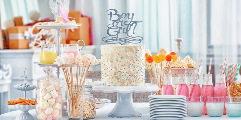 "Boy or girl" cake and different treats for baby shower party on table indoors